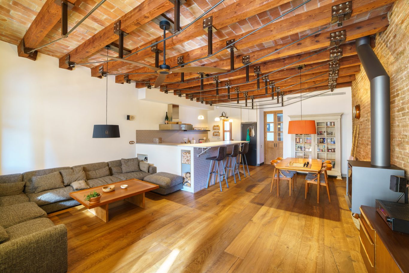 Eclano Sala de estar luminosa con techos de madera, sofá, mesa de café y barra de cocina.